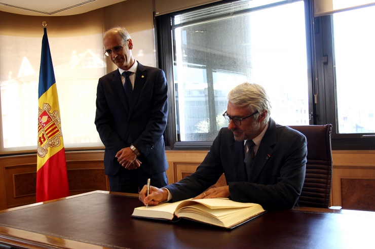 El director del Centre de Política Tributària i Administració de l'OCDE, Pascal Saint-Amans, signa el llibre d'honor sota la mirada del cap de Govern, Toni Martí.
