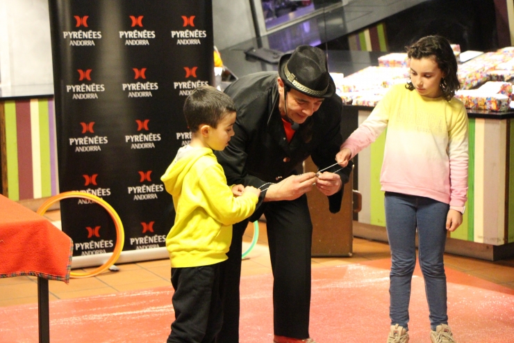 Un pallasso fent un truc de màgia a dos nens.