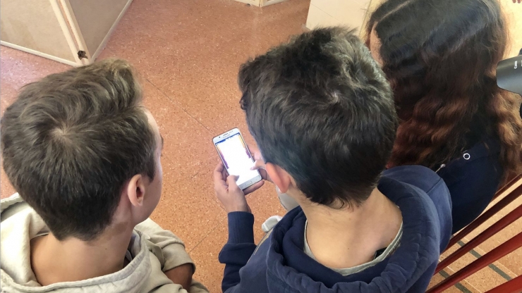 Alumnes d'una escola amb un telèfon mòbil.