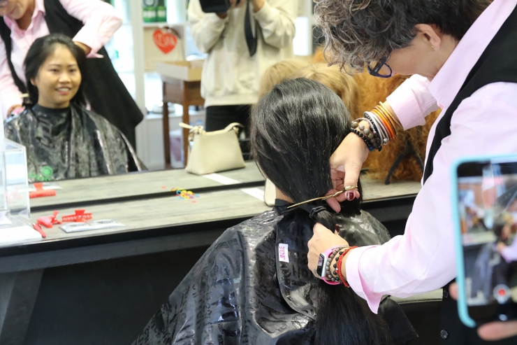 Nelly Garcia tallant els cabells a una clienta per a fer una perruca.