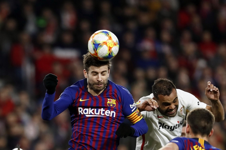 Pique rebutja un pilota de cap anticipant-se al jugador del Sevilla Mercado en el partit dels quarts de final de la Copa del dia 23.