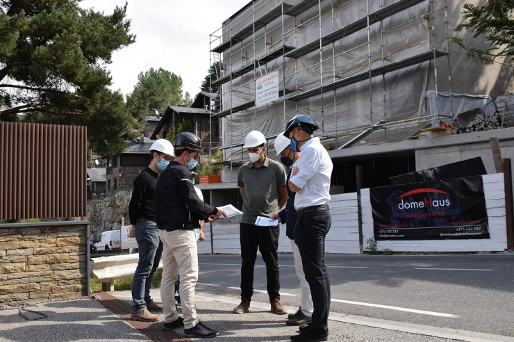 Els responsables de la construcció de la casa i els del ministeri de Medi Ambient conversen tot just al davant de l'edifici.