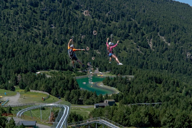 Dos turistes baixant per la tirolina situada al Mon(t) Magic de Canillo.