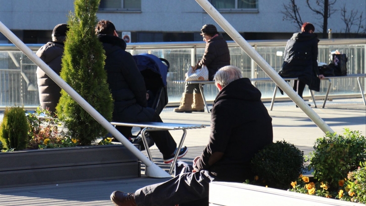 Diferents persones reposant en una zona de bancs.